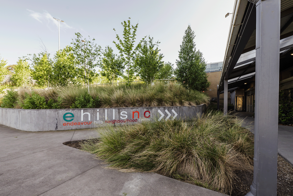 Lush grassy area outside of building entrance with a sign that reads Ehillsnc