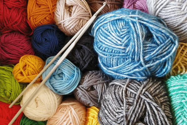 Balls of wool in knitting class with crochet hooks on top